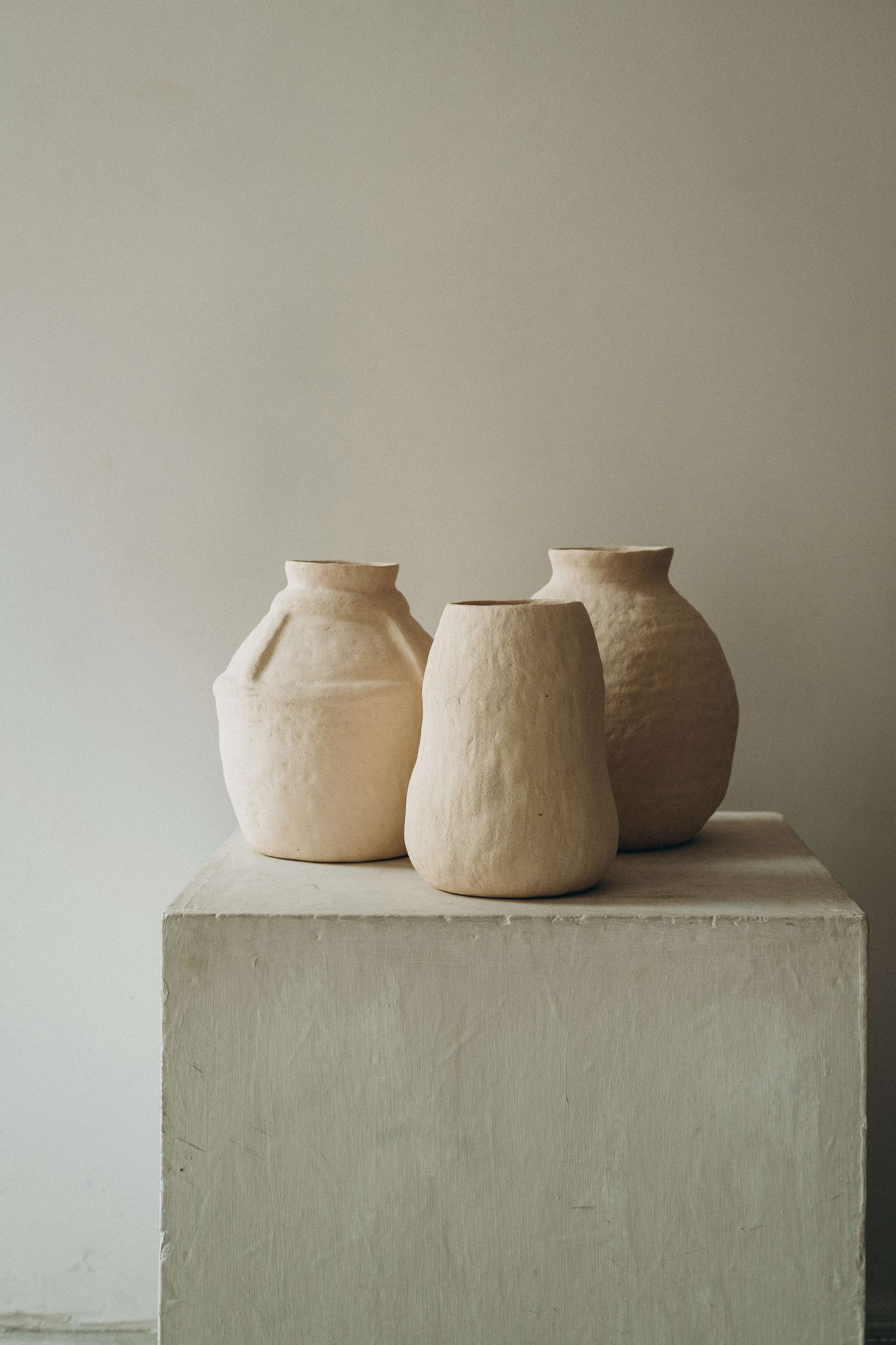 A wooden shelf displaying a variety of small, unglazed ceramic bowls and vessels.